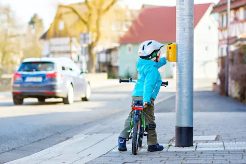 Sicherer Schulweg: Schüler auf einem Fahrrad betätigt eine Ampel